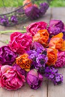 Fresh cut flowers on a table featuring Erysimum 'Bowles Mauve', Tulipa 'Orange Princess', 'Purple Peony' and 'Chato'