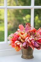 Bunch of Tulipa 'Malaika', 'Temple of Beauty', 'Floriosa' and 'Apricot Parrot' in a brass bucket on a windowsill