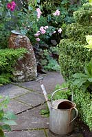 Antique garden ornaments: An old stadle stone used as a base for a sun dial an old galvanised watering can