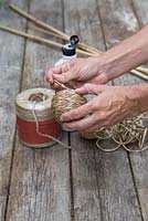 Using PVA glue to secure string around an old tennis ball to create cane toppers