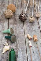 A variety of materials that can be used as cane toppers. Woven balls, tennis balls, wine corks, seashells, glass vases and bottles