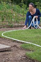 Marking out borders on newly laid turf using a coil of rope as a guide