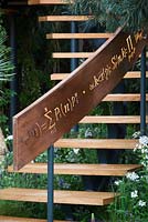 Illuminated mathematical symbols cut into band of copper to form bannister for staircase leading up the belvedere in the Winton Beauty of Mathematics,Chelsea Flower Show 2016.