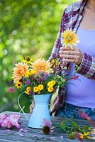 Woman making flower arrangement: dahlias, monarda, rudbeckia, persicaria amplexicaurus, gladiolus, chrysanthemum button yellow