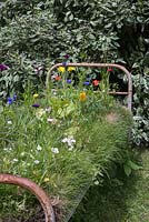 An upcycled metal frame bed featuring a turf base planted with Wildflowers