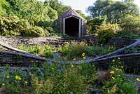 The Garden House, Devon, UK. The 'Ovals Garden' with steps and dry stone walls, cascading down a slope.