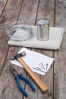 Materials required are some wire cutters, hammer, nails, sketch patterns, wire and a tin can