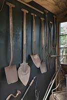 Traditional garden tools hanging inside black painted shed 