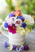 A container with grown cut flowers: cosmos, cornflowers, pinks, tobacco plant, rose buds and verbena.