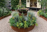 An Arts and Crafts inspired garden with a circular theme, raised corten steel borders, water feature and summerhouse. A Summer Retreat designed by Laura Arison and Amanda Waring. RHS Hampton Court Flower Show 2016