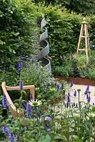 An Arts and Crafts inspired garden with handmade bench, obelisk and spiral sculpture. A Summer Retreat designed by Laura Arison and Amanda Waring. RHS Hampton Court Flower Show 2016