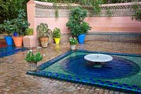 Low fountain and pool of water with blue and green glazed tiles in the Jardin Majorelle. Created by Jacques Majorelle and further developed by Yves Saint Laurent and Pierre BergÃ©, Marrakech, Morocco