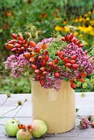Sedum 'Autumn Joy', wild rosehips, fennel and clematis seedheads arranged in stoneware vase