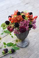 Sedum 'Autumn Joy', wild rosehips, rudbeckia seedheads and chrysanthemums arranged in small metal pot