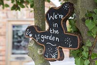 Oak tree slice painted and decorated to display 'We're in the garden'