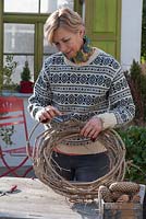 Woman making wreath with clematis and conifers