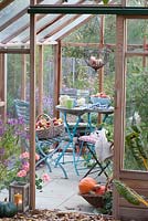 Small seating area in the greenhouse, fresh picked apples and pumpkins in baskets 