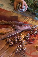 Spray painting goose feathers and rose hips gold
