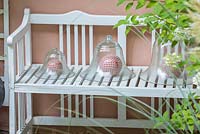 Decorative bell jars with red and white chequered spheres on a white wood bench