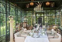 Formally dressed table inside historic Art Deco glasshouse with iron oven - fireplace and lighting 