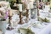 Detail of formal dining table with silver candle holders, white porcelain and silver cutlery