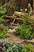 Rustic wooden saw horse with logs and axe, woodland planting - The Woodcutter's Garden - RHS Malvern Spring Show 2016. Designer: Mark Walker, Sponsor: Howards Motors