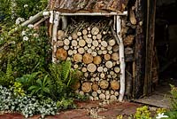 Rustic covered log store and woodland planting - The Woodcutter's Garden - RHS Malvern Spring Show 2016. Designer: Mark Walker, Sponsor: Howards Motors