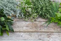 Bay, Curry Plant, Marjoram, Rosemary, Chives and Mint on wooden surface
