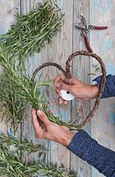 Tying Rosemary around wreath with string