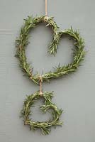 Wreath constructed from Rosemary hanging against wooden surface