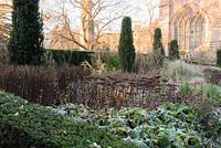 The hot border in the East Garden of the Bishop's Palace garden, where fastigiate Irish yews stand sentinel over a rich mix of herbaceous perennials, shrubs and grasses including sedums, Phlomis russeliana, dahlias and bananas