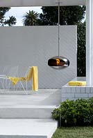 A modern outdoor pavilion with a seating area and a suspended cocoon fireplace
