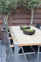 Seating with table and chairs, containers with Olea europaea