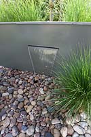 Wall fountain and paving with pebbles underneath.