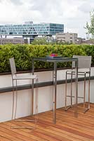 Roof garden with decking terrace, bar stools and table. View on the city Rotterdam, Holland.
