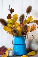 Fagus - Copper Beech leaves and teasels arranged in blue enamel pot