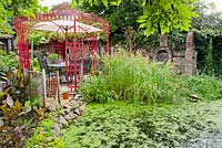 Painted wrought iron gazebo by the pond.