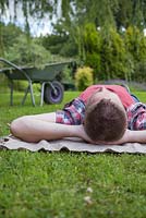 Man laying on a rug in the garden relaxing