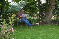 Man sitting down relaxing in the shade reading a magazine