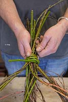 Conceal the string by wrapping Willow stems around it, as well as strengthening the wreath