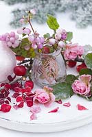 Frosted display of Snowberries in a glass jar, with red Crab apples and pink Roses on a white tray