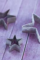 Metal star shaped cookie cutters on a frosted purple table