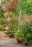 Gravel path, metal chicken ornament, sedum pennisetum, wooden support, salvia bethellii.  Owner of Daisy Roots Nursery, Anne Godfrey's private garden, Hertfordshire. 