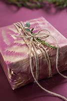 A wrapped present with Fern foliage and Eucalyptus, with spray painted imprint of a Fern