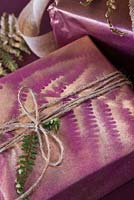 A wrapped present with Fern foliage and Eucalyptus, with spray painted imprint of a Fern