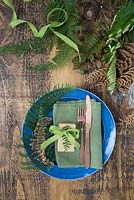 A table place setting with gold spray painted Fern and green Fern fronds
