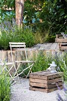 Rustic style sitting area with chairs and crate as a table surrounded by Lavender garden. The Lavender Garden, Designers: Paula Napper, Sara Warren, Donna King. Sponsor: Shropshire Lavender. Sponsor: Shropshire Lavender. RHS Hampton Court Flower Show 2016 