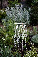 White metal mobile from Habitat in the white garden. Plants include  Phlox 'White Flame', white geranium, Artemisia ludoviciana 'Silver Queen' and Stachys byzantina