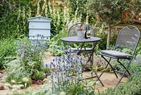 Seating area with a wooden beehive, Eryngium bourgatii, Pennisetum villosum, and Verbascum 'Album' - The Drought Garden, RHS Hampton Court Palace Flower Show 2016