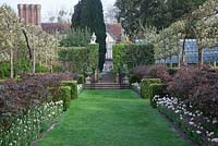 Rose Walk, Pashley Manor. View to the house with  Espaliered Pear Trees underplanted with Rosa 'Irene Watts' and Tulipa 'Angelique' with pink Forget-Me-Nots.